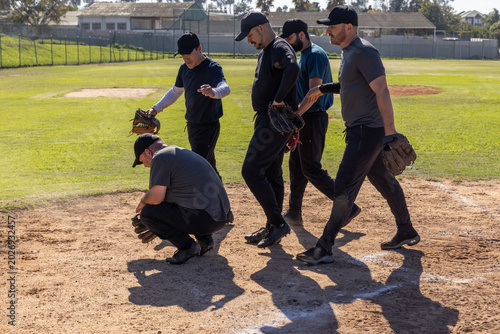 Obraz na plátně Diverse male baseball teammates standing on infield near base path, wearing caps