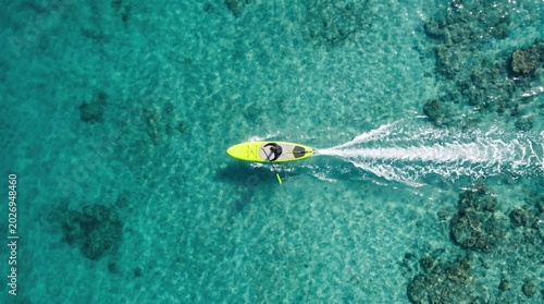 Aerial view of yellow kayak in clear reef water; sustainable coral reef conservation tourism.