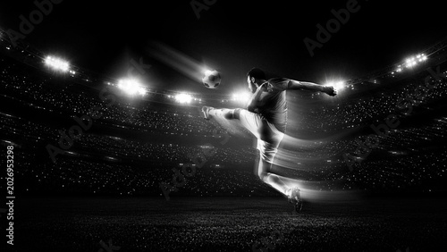 Tablou pe pânză Soccer player performing flying kick under stadium floodlights in black and white