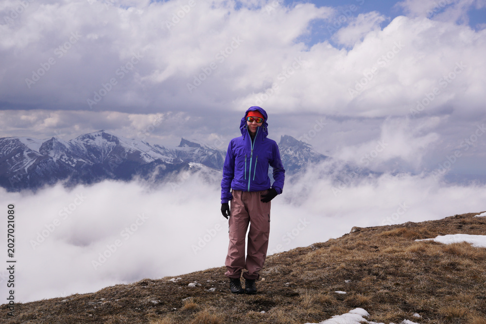 Obraz premium a young tourist in front of snow-covered mountains and clouds. Outdoor travel and an active lifestyle