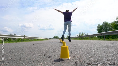 An adult woman is learning to roller skate. She is using yellow cone chips.