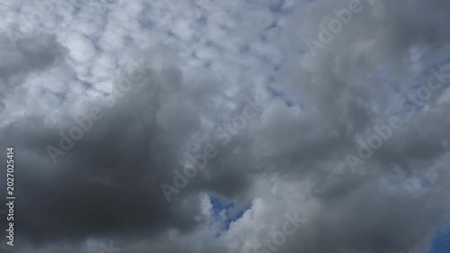 Diffuse white summer clouds move across the blue sky in this time lapse. The sky fills the frame.
