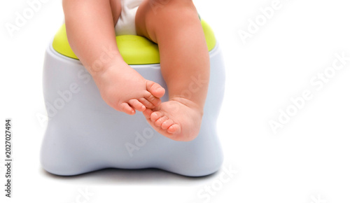 Chubby legs of a baby sitting on a potty training chair isolated