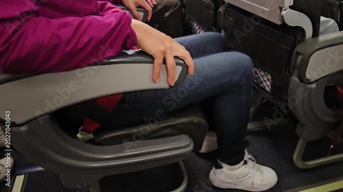 A woman sits on a plane, clutching her seat, afraid of flying. Aerophy and the fear of flying concept