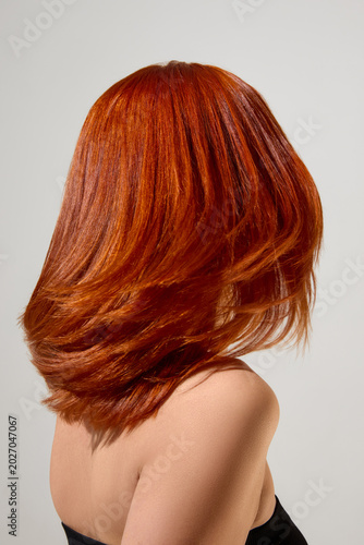 Fotografie Smooth copper red hair in glossy motion after salon color care treatment