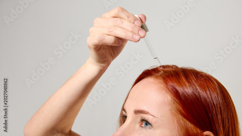 Foto Close up of hair serum drops on glossy red hair roots
