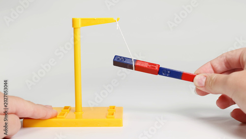 Photos Hands Demonstrating Magnetic Attraction and Repulsion With Suspended Bar Magnets