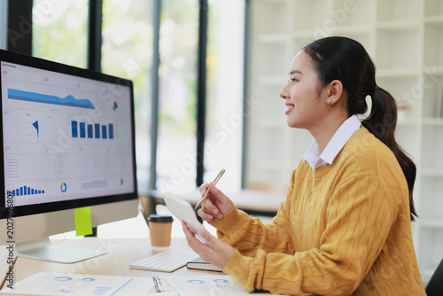 Foto Young Asian professional business woman calculating finances and analyzing data