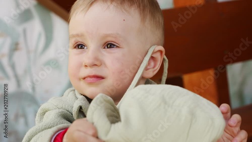 Child wears a hat and explores the fabric in a simple setting