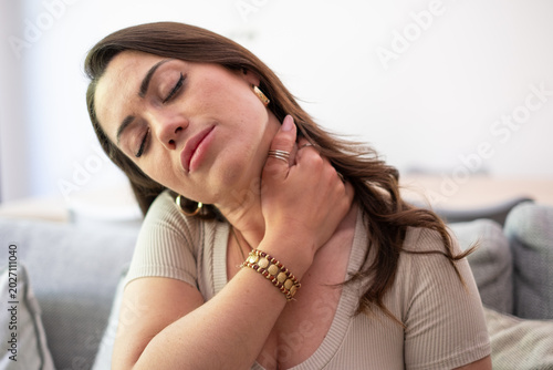 Foto Young Woman Massaging Neck Pain While Resting On Couch Showing Discomfort And Mu