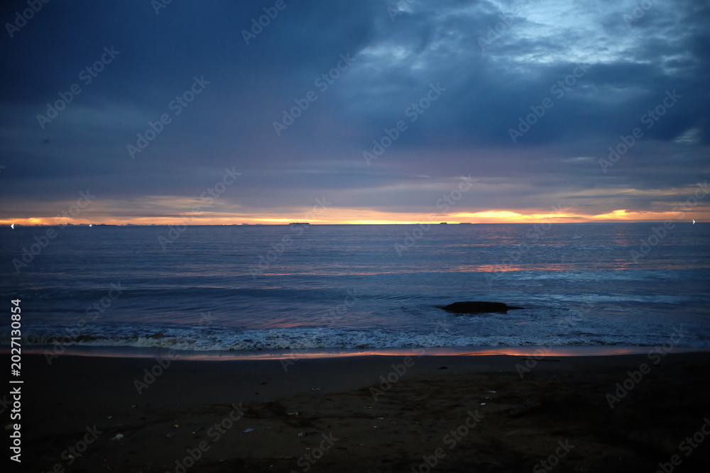 Obraz premium Coastal Sunset Under Heavy Clouds