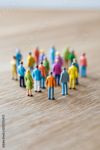 A vibrant group of miniature people gather on a light wooden surface