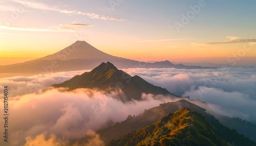 Mountain peaks above clouds, with larger mountain silhouetted at sunrise