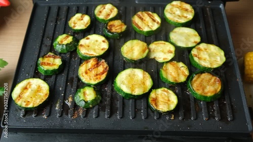 Close-up of Fresh Green Zucchini Rounds Roasting on Contact Grill.