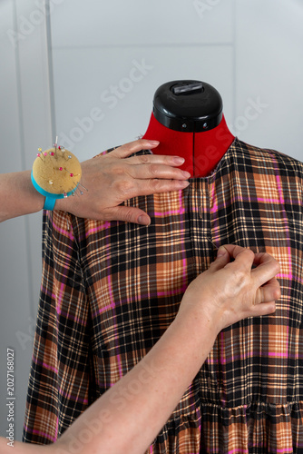 Fotografija Vertical close up of woman adjusting and pinning fabric on tailor mannequin during fitting and dressmaking process