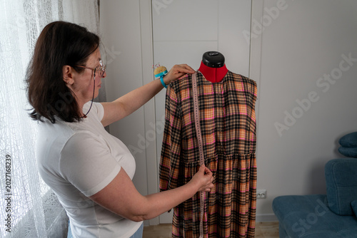 Фотография Woman taking body measurements on professional tailor mannequin during dressmaking and sewing process in atelier
