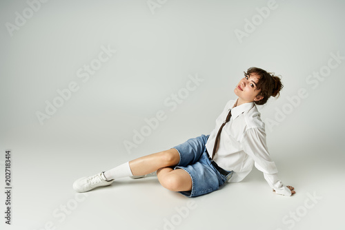 Foto Young woman showcases trendy style in a modern studio setting with a charming po