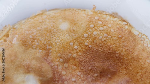 Rustic style thin pancake on plate. Closeup of homemade pancake with bubbly golden surface. Artistic shot of homemade pancake highlighting crisp edges and tender interior