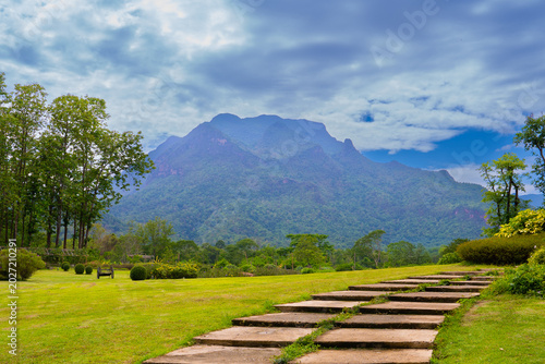 Fotografie Doi luang Chiang Dao mountain rises behind green garden and stone steps under cl