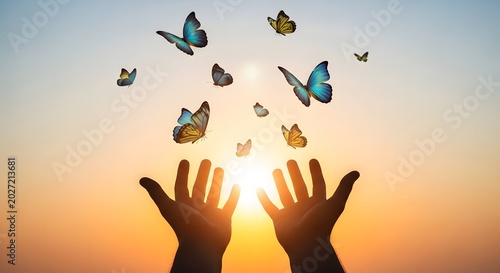 Flying butterflies emerging from open hands toward a bright sunset sky