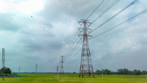 Photos Electricity transmission pylons crossing green agricultural field under cloudy s