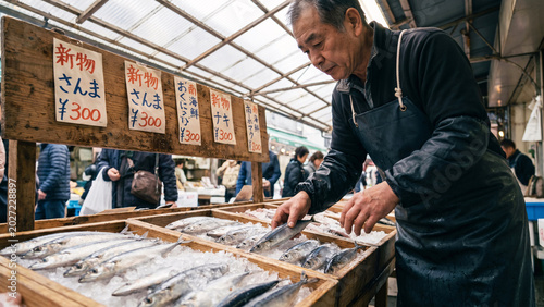 Male Fish Vendor in Rubber Apron Arranging Fresh Mackerel on Crushed Ice at Tsukiji Outer Fish Market in Tokyo, Japanese Seafood Trade, Documentary, Working Lifestyle