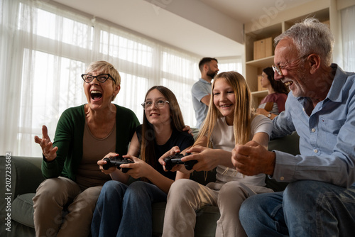 Kids gaming on console with grandparents cheering in living room