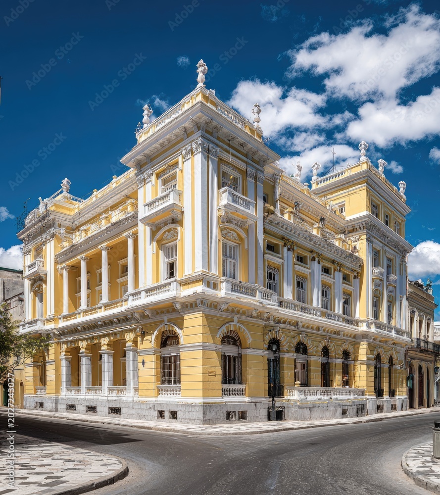 Obraz premium Ornate yellow building with classical architecture and balconies on a sunny day