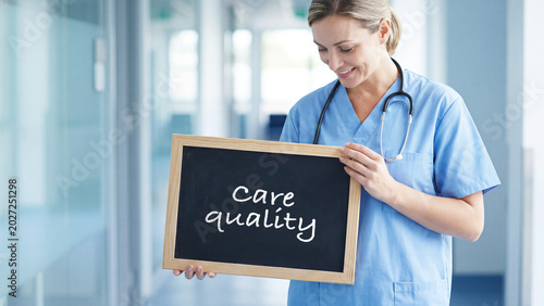 Healthcare professional nurse holding a chalkboard with care quality text in hospital corridor, medical staff assurance, healthcare service excellence and patient satisfaction concept