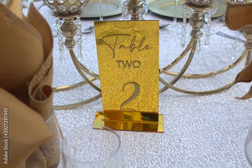 Photography Elegant oceanfront wedding reception table setting with gold accents