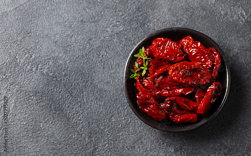Sun dried tomatoes with fresh herbs and spices. Grey background. Close up. Copy space. Top view.