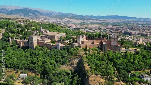 High angle view of the historic Alhambra palace complex and Alcazaba fortress in Granada. Famous UNESCO medieval Moorish architecture surrounded by scenic Andalusian mountains in Spain.