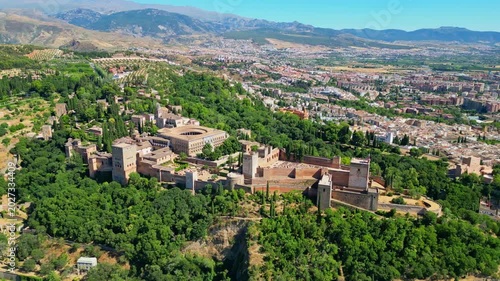 High angle view of the historic Alhambra palace complex and Alcazaba fortress in Granada. Famous UNESCO medieval Moorish architecture surrounded by scenic Andalusian mountains in Spain.