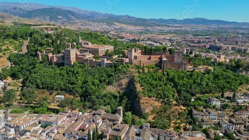 High angle view of the historic Alhambra palace complex and Alcazaba fortress in Granada. Famous UNESCO medieval Moorish architecture surrounded by scenic Andalusian mountains in Spain.