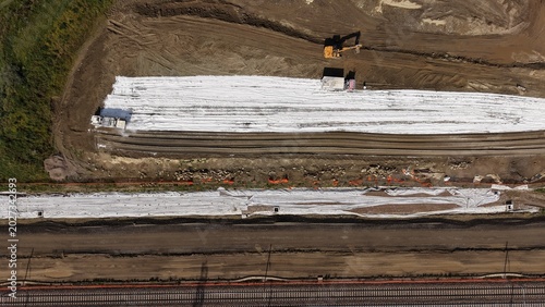 Heavy machinery compacting stabilized soil at railway infrastructure construction site from above