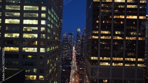 Dutch tilt perspective between modern office buildings into canyon of skyscrapers revealing urban street scene with heavy traffic in downtown Toronto at night