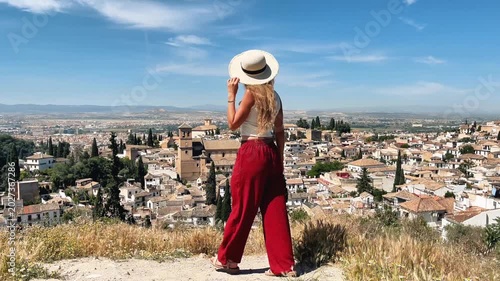 Woman Traveling in Red Pants Overlooking a Majestic Spanish Hillside City, Granada in Andalusia. Discovery and Contemplation 