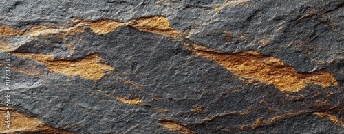 Close-up texture of rough dark grey slate interwoven with thin veins of golden-brown mineral