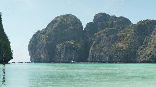 Serene Tropical Beach with Turquoise Water and Towering Limestone Cliffs Under Clear Blue Sky Creating Tranquil Atmosphere