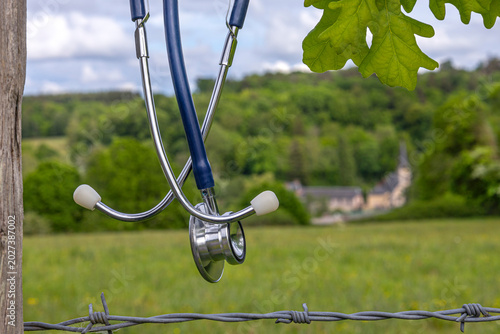 Stethoscope Hanging on a Fence by a Field-The concept of a medical desert, a shortage of rural doctors