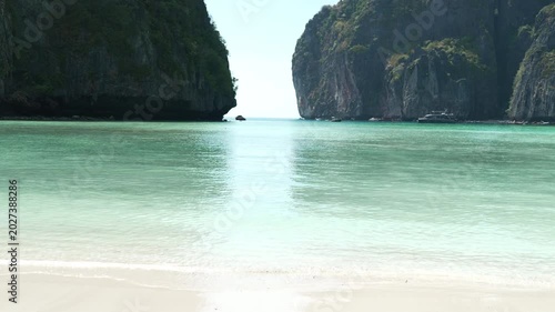 Serene Tropical Beach with Clear Turquoise Water and Towering Cliffs Creates Tranquil Atmosphere and Paradise in Natures Embrace