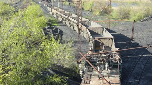 Top view of industrial electric locomotive OPE-1A moving freight railcars through mining and industrial area. Heavy railway transport filmed from elevated position.