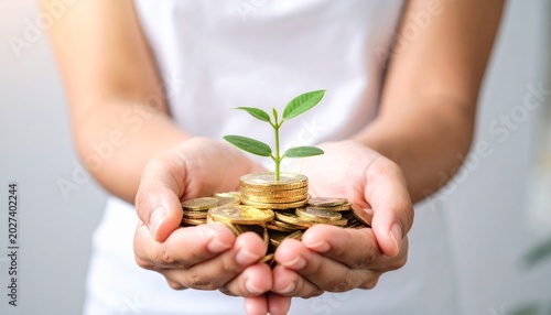Cupped hands holding gold coins with a green seedling growing from the top