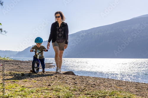 Mother Teaching Son To Ride Balance Bike Along Cultus Lake Shore In Chilliwack, BC, Canada