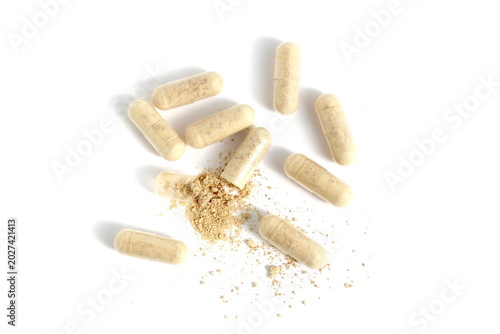 There are many transparent capsules with beige medicine on a white background.