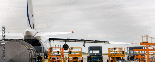 Bild auf Leinwand Cargo aircraft undergoing maintenance on airport apron hydraulic platforms service equipment cloudy sky