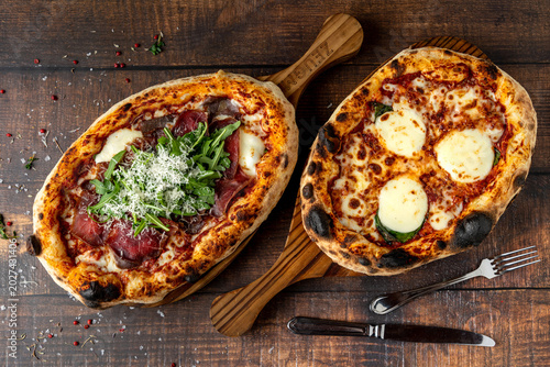 Two artisan italian pizzas on rustic wooden table top view