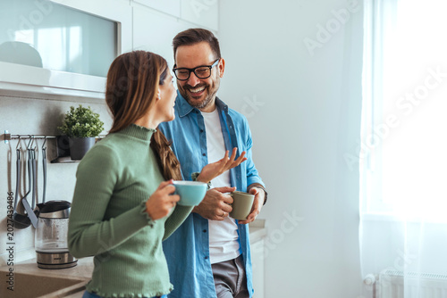 Smiling Couple Having Coffee and Conversation in Bright Modern Kitchen During Morning Routine
