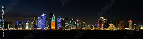 Photography DOHA, QATAR – The modern skyline of Doha glitters with illuminated skyscrapers along the waterfront at night, showcasing Qatar's capital as a futuristic Arabian Gulf metropolis