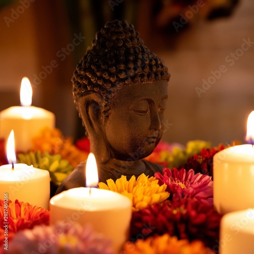 Buddha Statue Surrounded by Candles and Flowers During Evening Gathering for ...